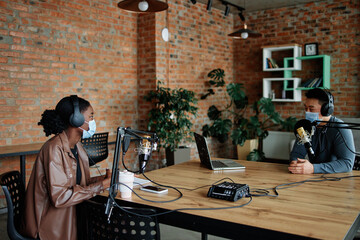 Man and woman working in professional podcasting studio during epidemic 