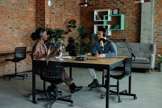 Man and woman recording their conversation for podcast