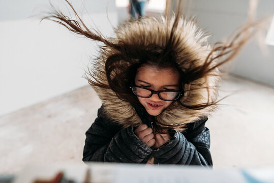 Girl playing in fan as hair blows. 