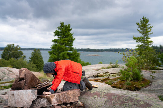 Boy Building Campfire on Sea Kayak Wilderness Camping Trip to Remote Island