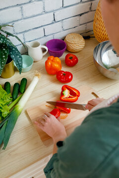 Crop unrecognizable woman cutting bell pepper in kitchen