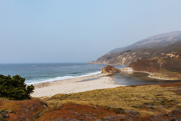 Ocean and cliffs with a deserted beach on a half foggy day