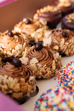 Fancy decorated cupcakes in a pink and brown bakery box