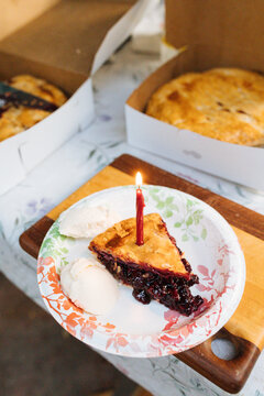 A slice of summer cherry pie sits on a paper plate at an outdoor party