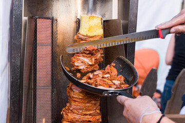 Street vendor cutting grilled al pastor meat