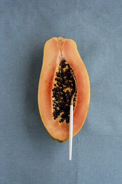 Half cut papaya on blue linen background with spoon