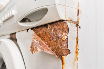 Rusty peeling corner layer from an old broken washing machine. Home appliances wear concept