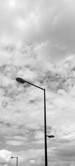 Minimalist photo composed by a lamppost, with clouds of a cloudy day in the background. In black...