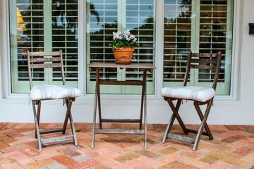 Wooden chairs and table outside a house, front porch area. Summer style