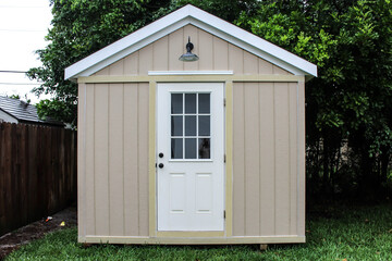 Front view of a backyard tool shed with a dog outside in a yard. Many trees are surrounding the...