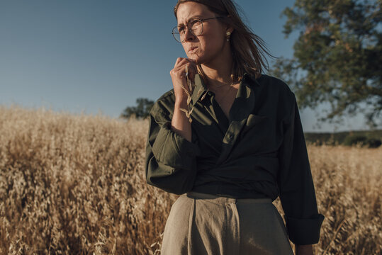 Portrait of a woman with grass straw in her mouth standing at th