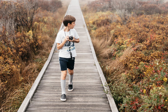 boy with camera on boardwalk in nature park