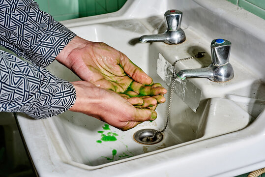 man washes his hands with a green liquid soap