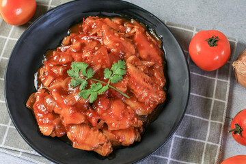 Chicken with tomato and vegetables close-up on plate. Asian food and meal.