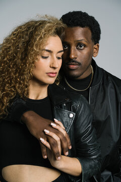 Stylish multiracial couple cuddling in studio