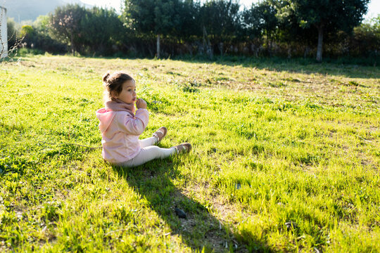Two years old baby playing in the grass in a bright sunny day of spring