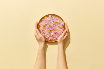 Woman holding plate with flowers in ice cubes