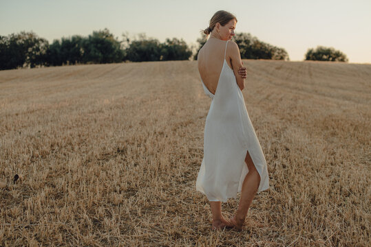 Woman in camisole dress standing barefoot on a mowed field