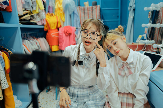Two young Asian women take pictures and live broadcast with cell phone