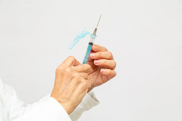 detalhe das duas mãos da enfermeira segurando uma seringa, verificando a dose do medicamento - obrazy, fototapety, plakaty