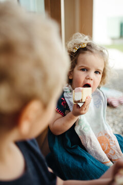 Close up of a young brother and sister eating ice cream outdoors
