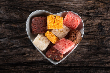 Coconut candy coconut, Brazilian sweet in a heart-shaped bowl on a rustic wooden background