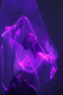 Sensual woman with veil in neon illumination
