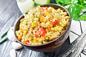 Barley porridge with minced meat in bowl on wooden board
