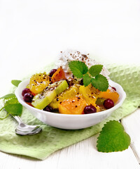 Salad fruit with cranberries in bowl on light wooden board