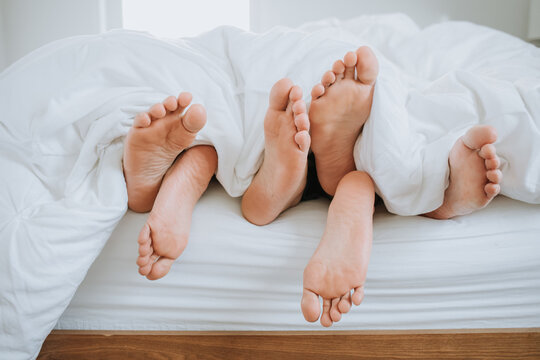 Closeup of Three Pairs of Feet in Bed