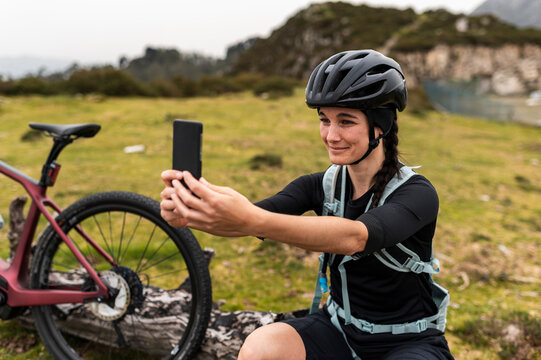 Modern cyclist taking selfie on smartphone in mountains  