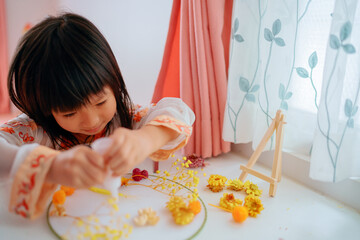 Asian kid making dried flower fan decoration DIY