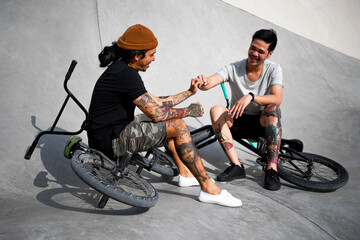 Two young tattooed men on BMX bikes.