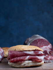  S&aacute;ndwich de bondiola de carne de res. Concepto de alimentaci&oacute;n tradicional realizada en casa. Chorizos o salchichas caseras en tabla de madera. 
