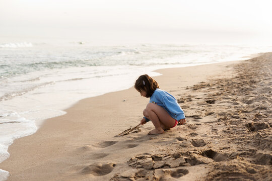 Child Writing Her Name In The Sand