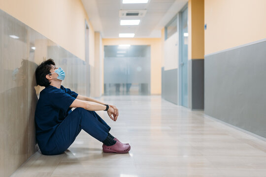 A woman doctor sitting in the corridor of a hospital tired and sad