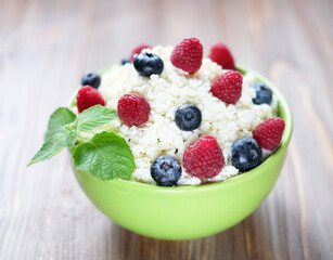 Cottage cheese with fresh raspberries and blueberries in a bowl for healthy breakfast