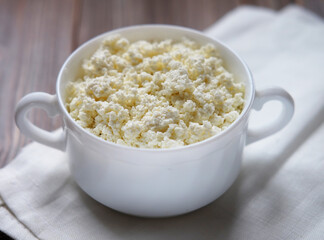 Cottage cheese with mint in a white bowl on a white napkin.