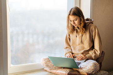 woman freelancer works at the laptop on the windowsill