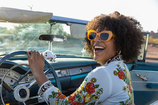 Attractive Black woman behind wheel of Vintage car 