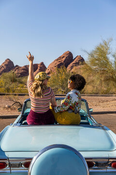 Two Friends sitting in Convertible car together on Road trip in desert southwest 