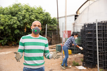 Portrait of farmer wearing protective mask in the backyard of country house