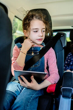 Little girl using her tablet inside a van
