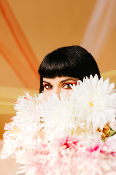 Studio Portrait of a girl hiding behind a bouquet of flowers