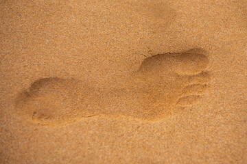 Fototapeta na wymiar Footprints barefoot in the desert sand. Foot print in the sandy beach, close up.