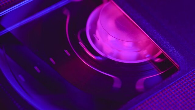 VHS video cassette insert in the VCR, play, stop, eject, close up, blue and purple light