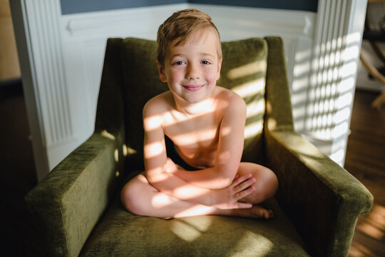 Cute young boy sitting a chair with light and shadow falling on him