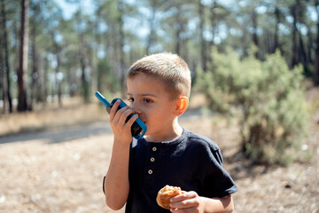 Boy playing with a walkie talkie in the forest.