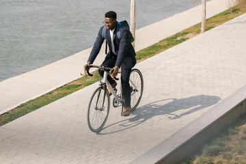 Young african american businessman riding a bicycle to work in the urban city zone 