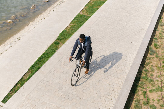 Young african american businessman riding a bicycle to work in the urban city zone 